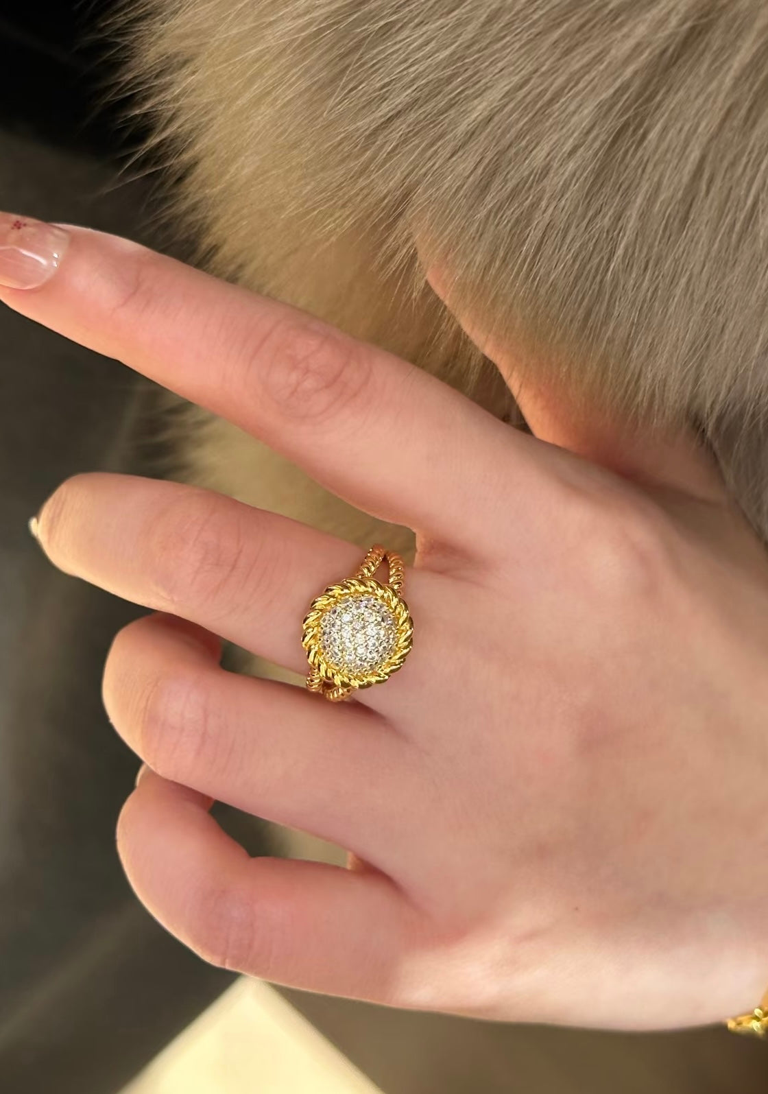 Close-up of a hand wearing a gold ring with a diamond design.