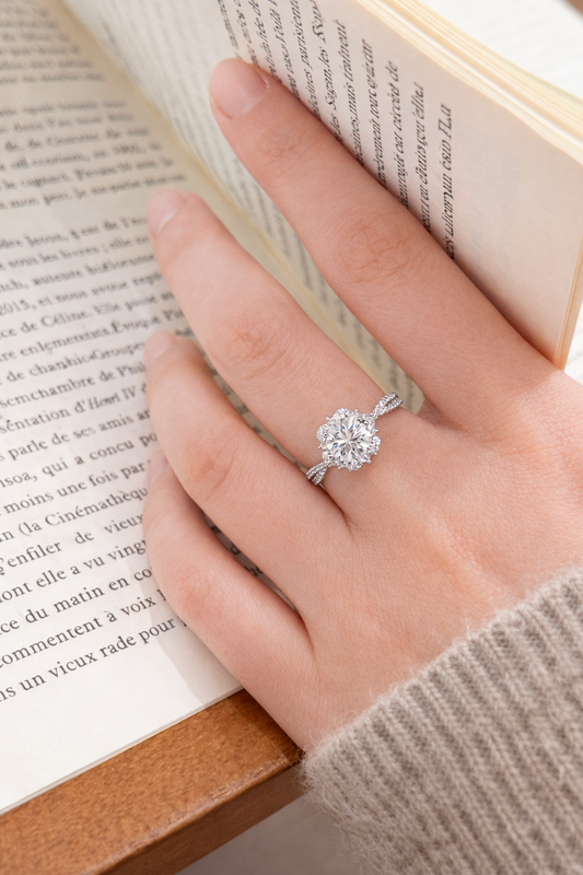 Hand wearing a diamond ring with an open book in the background