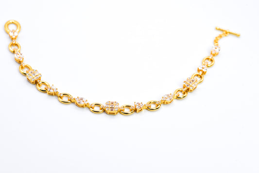 Gold color bracelet with gemstones on a light gray background