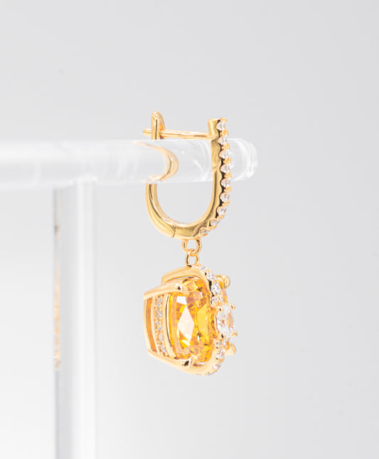 Gold color hoop earring with a central gemstone on a white background