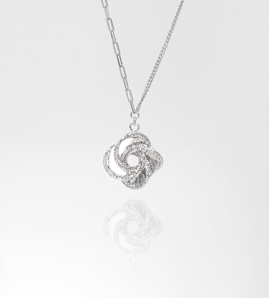 Silver necklace with a intricate pendant on a light gray background