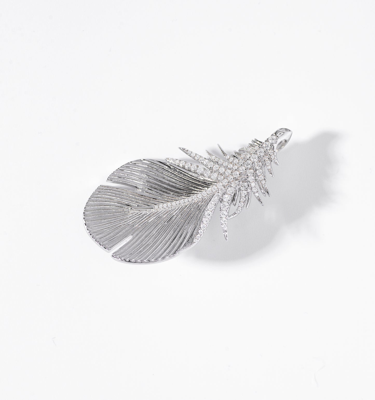 Feather-shaped jewelry piece with gemstones on a white background