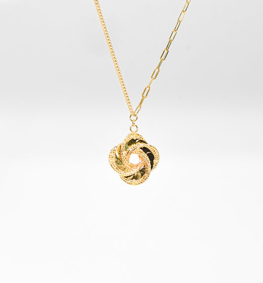 Gold color necklace with a unique pendant on a light gray background
