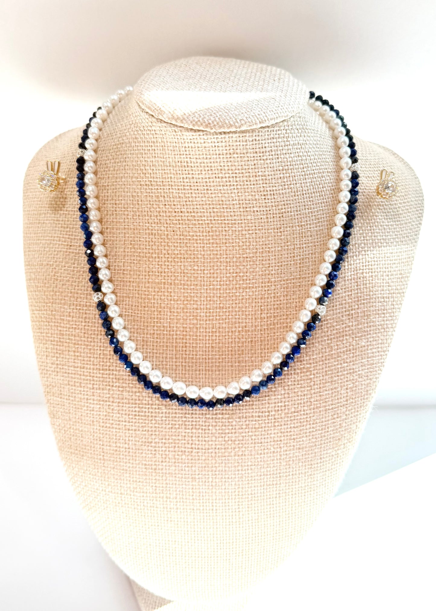 Pearl and blue beaded necklace on a mannequin bust with matching earrings.
