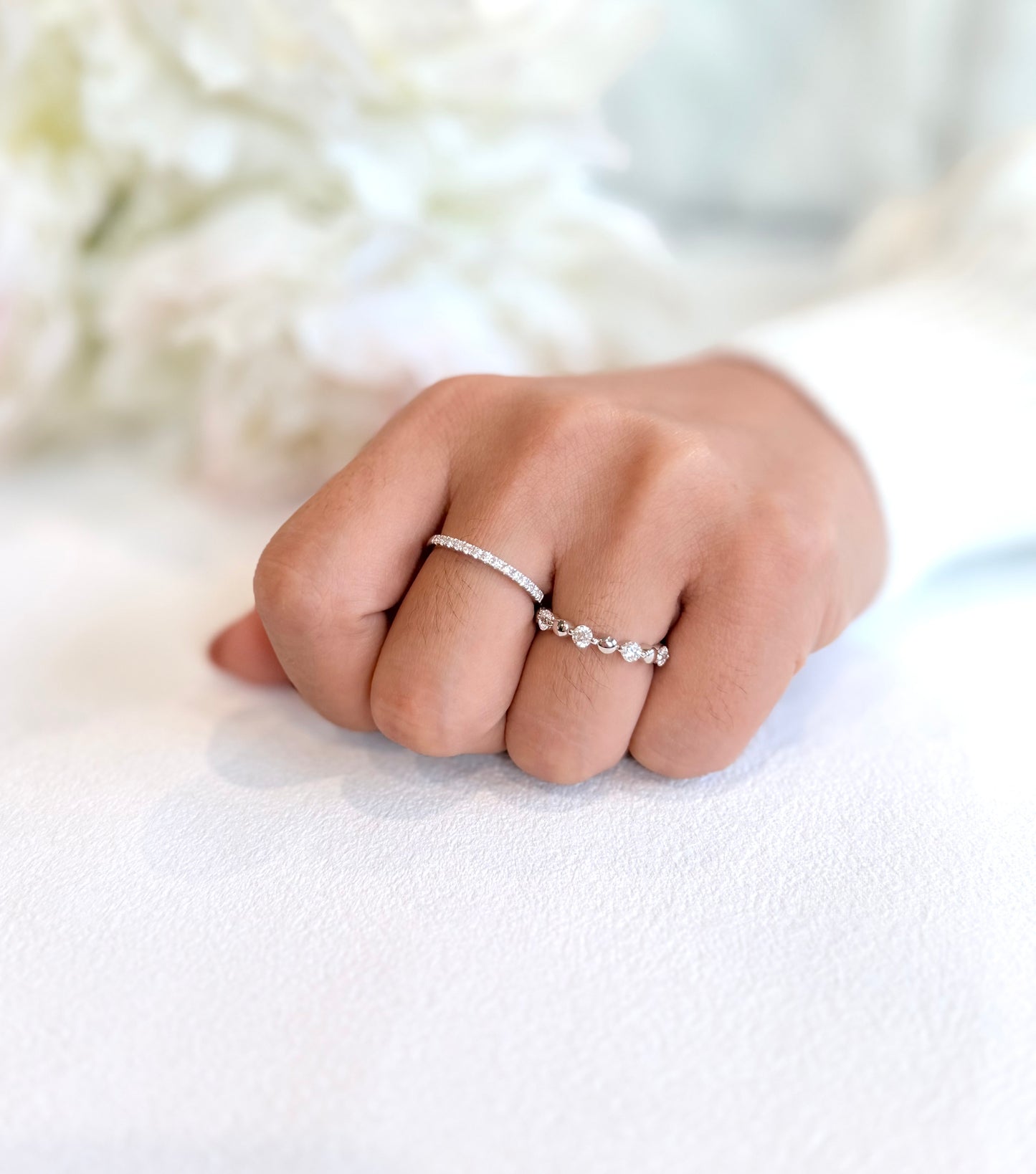 Hand wearing two silver rings on a white background