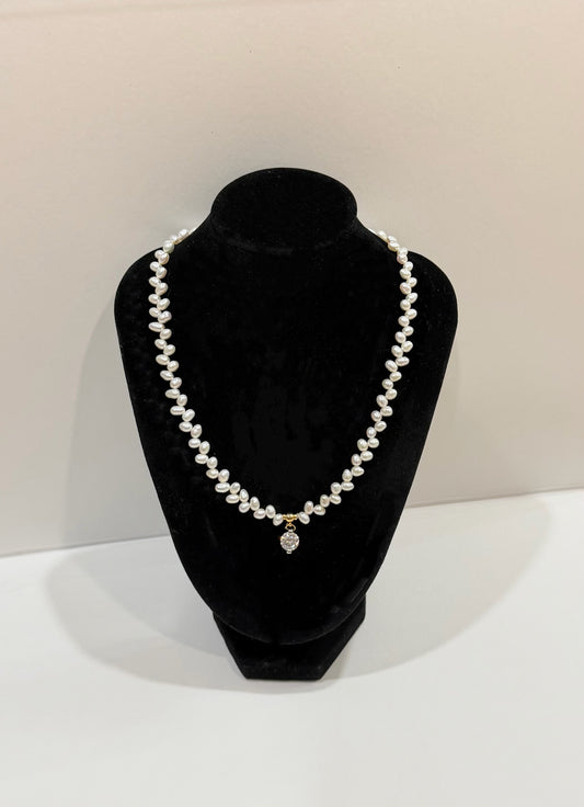 Pearl necklace on a black velvet bust against a neutral background