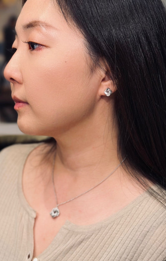 Close-up of a person wearing earrings and a necklace with a neutral background