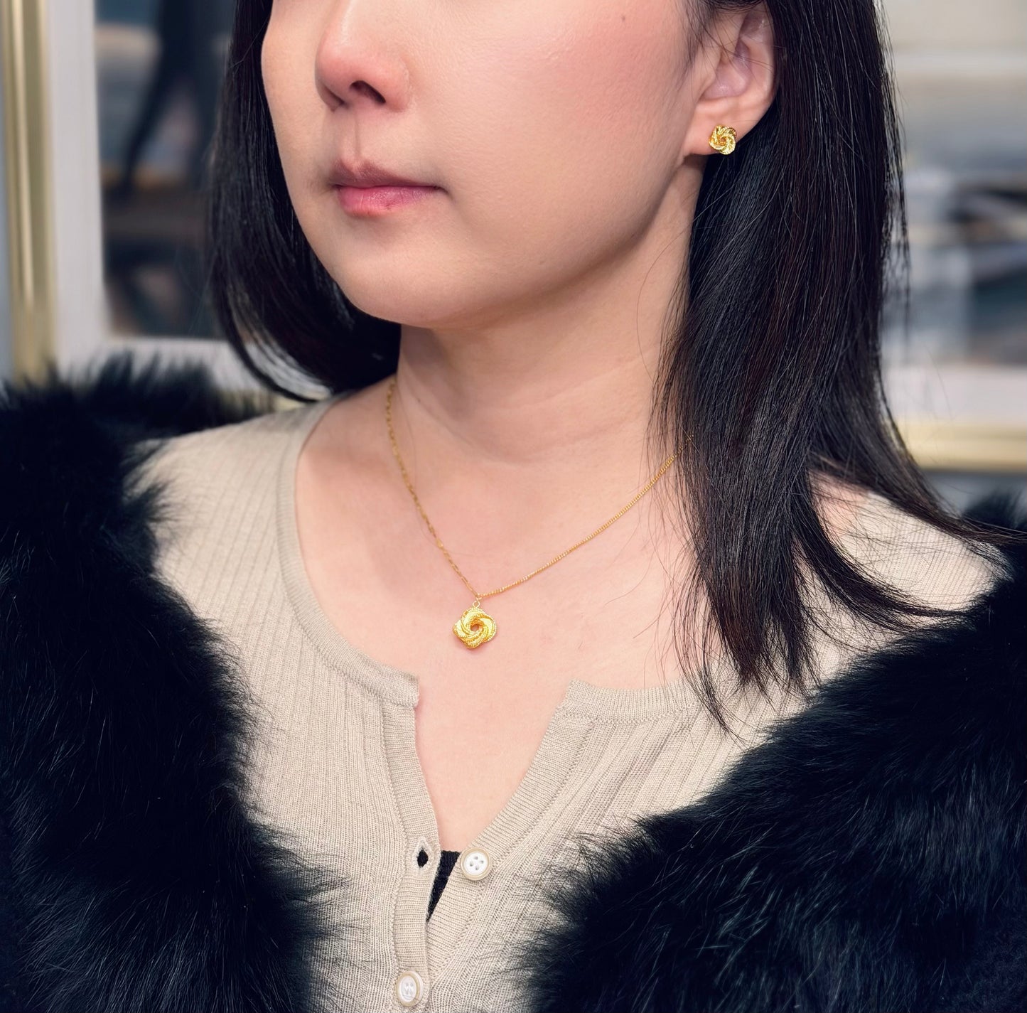 Woman wearing gold color necklace and earrings with a blurred background
