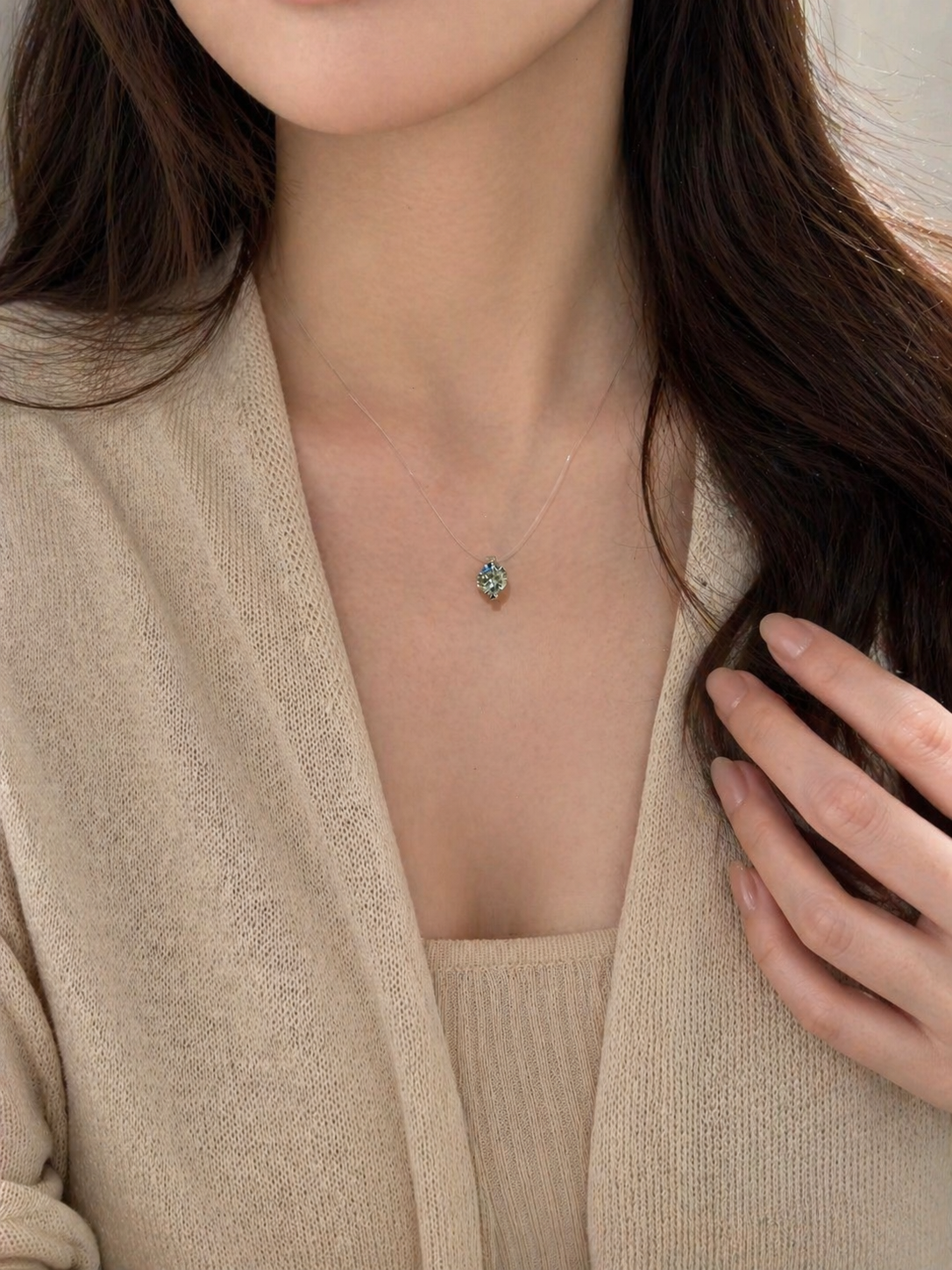 Person wearing a delicate necklace with a small pendant, set against a neutral background.