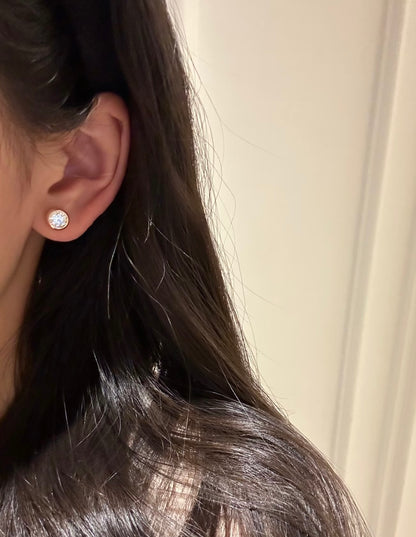 Close-up of a person wearing a  Cubic Zirconia  earring with a neutral background