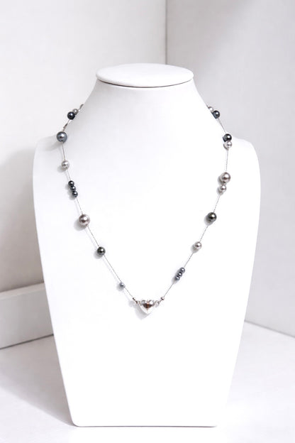 Necklace with black and gray beads on a white mannequin bust against a white background
