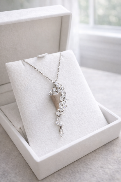 Silver necklace with a floral pendant on a white jewelry display box.