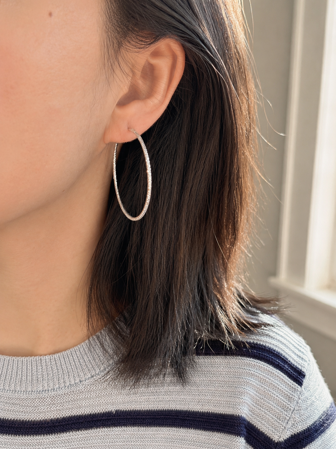 Person wearing a hoop earring with a neutral background