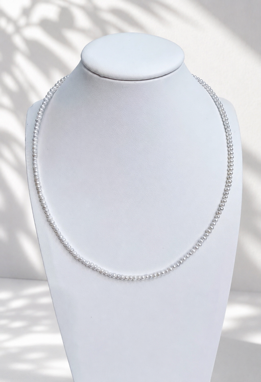 Lunelle by Heart and Hand mini freshwater pearl necklace with small white pearls and delicate chain, close-up view.