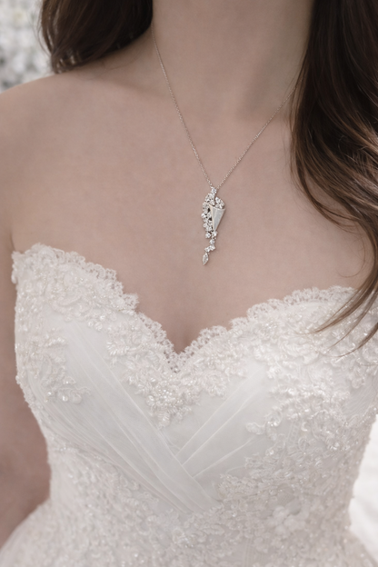 Close-up of a woman wearing a delicate necklace with a white lace dress.