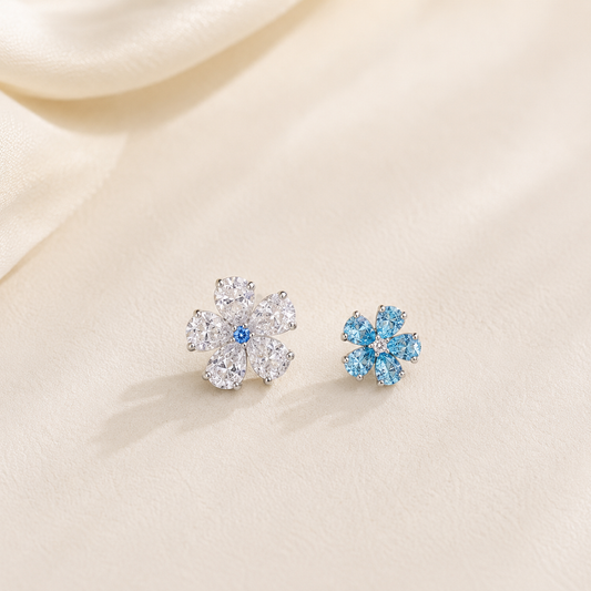 Lunelle Atelier twin bloom blue and white mismatched flower stud earrings on ears, showcasing floral jewelry design.
