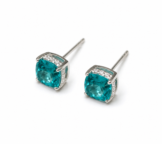 Lab-grown Paraiba cushion-cut stud earrings by Lunelle Atelier featuring vibrant blue-green gemstones and silver settings.