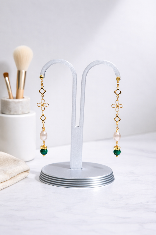 Pair of earrings on a white stand with a neutral background