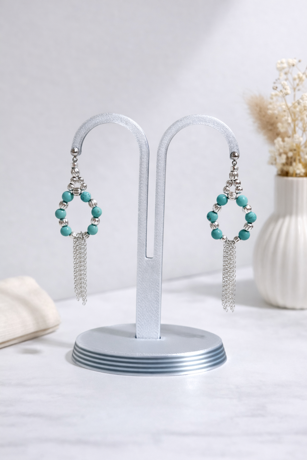 Turquoise beaded earrings on a white stand with a light background