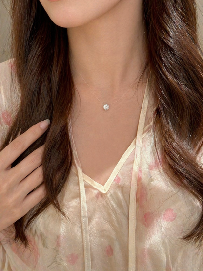 Close-up of a delicate necklace with a small diamond pendant worn by a person with long brown hair.