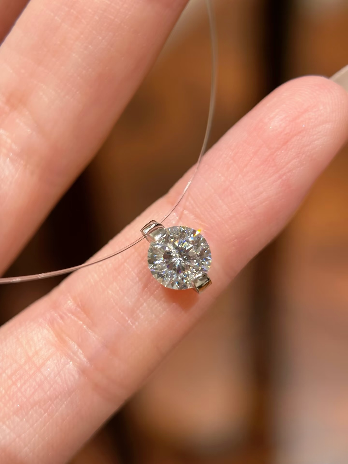Diamond ring held between fingers against a blurred background