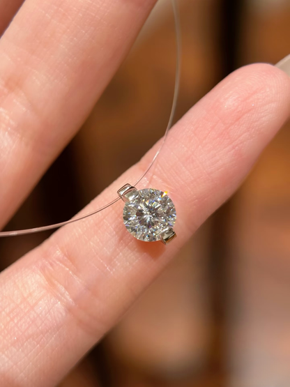 Diamond ring held between fingers against a blurred background