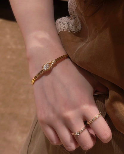 Lunelle Atelier teardrop solitaire open bangle bracelet with elegant gold finish and delicate design on a white background.