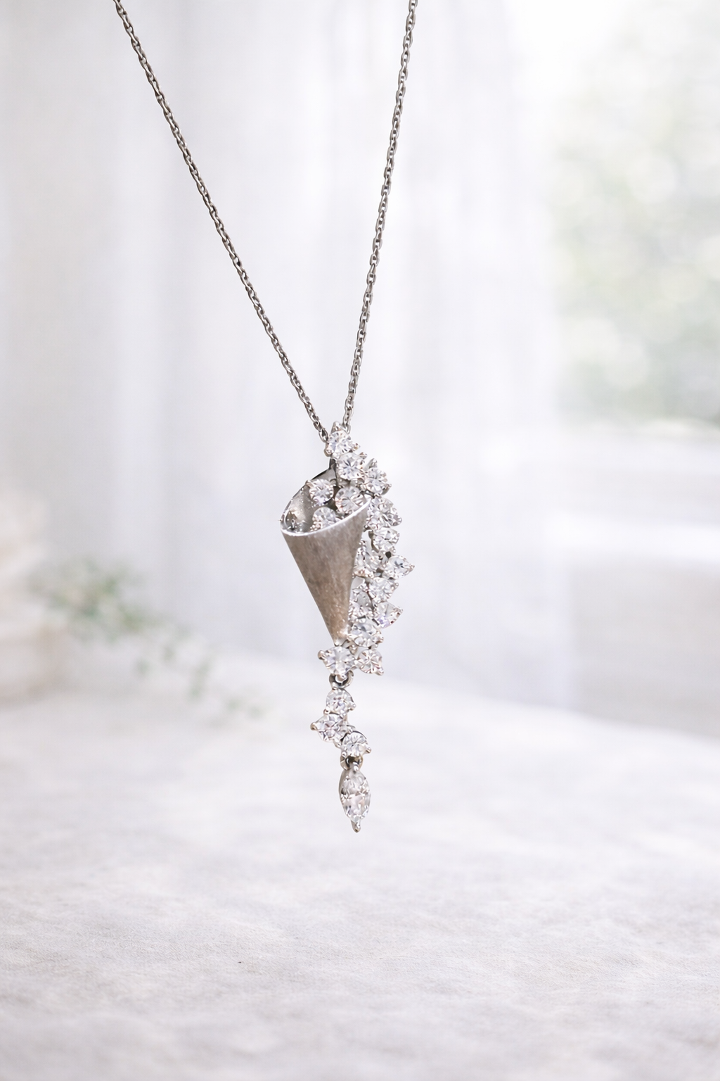 Diamond necklace with a cone-shaped pendant on a blurred background