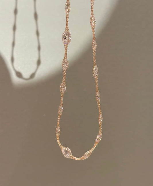 Delicate gold necklace with small diamonds on a neutral background