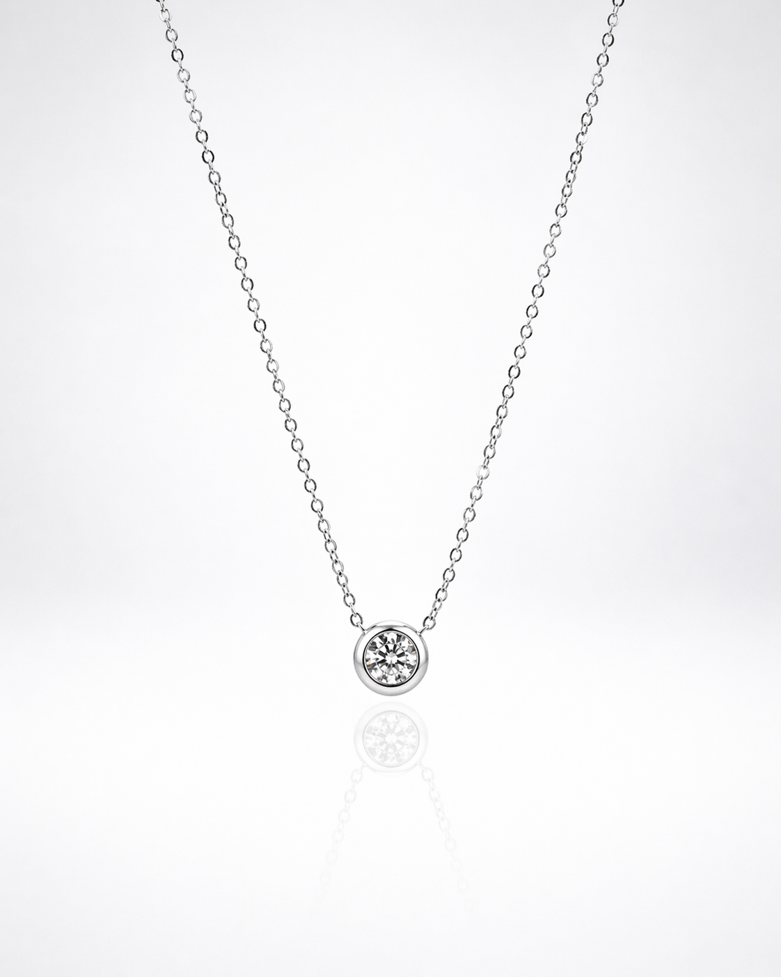 Silver necklace with a small round pendant on a white background