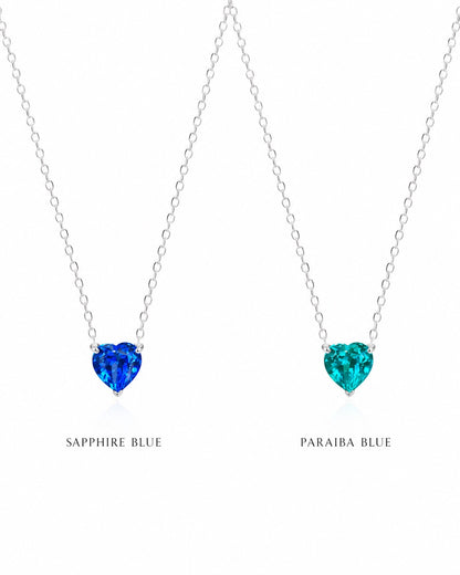 Two heart-shaped gemstone necklaces, one sapphire blue and one paraiba blue, on a white background.