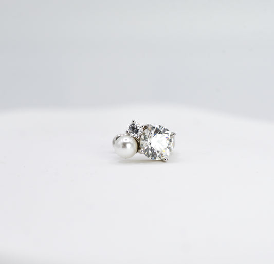 Pair of earrings with a pearl and a clear gemstone on a light gray background