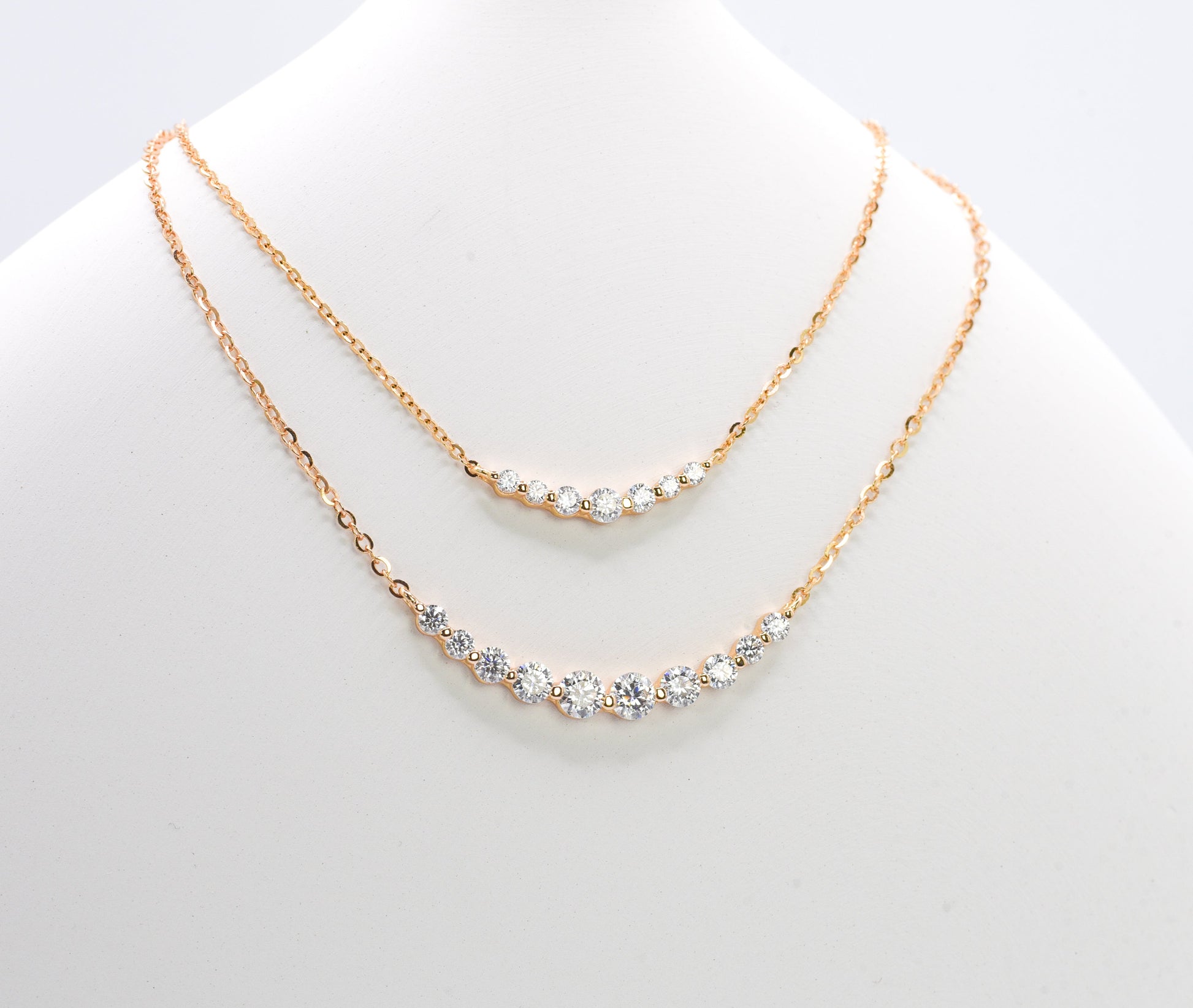 Two gold color of necklaces with gemstones on a white mannequin.