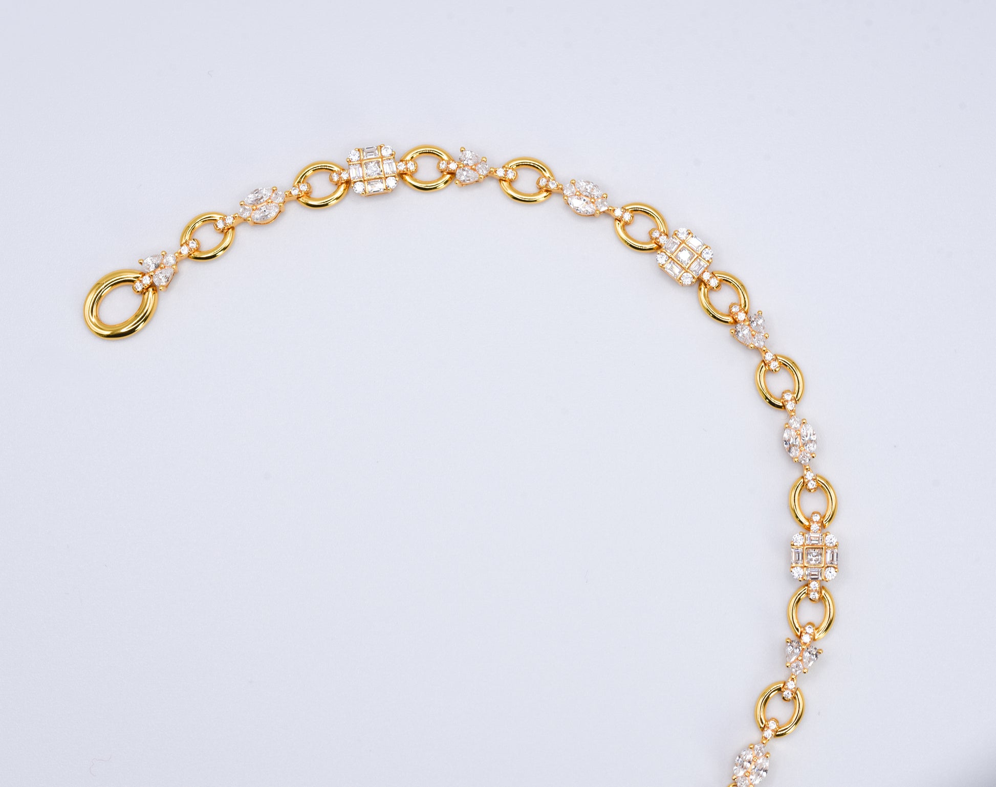 Gold color bracelet with gemstones on a light gray background