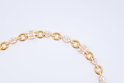 Gold color bracelet with gemstones on a light gray background