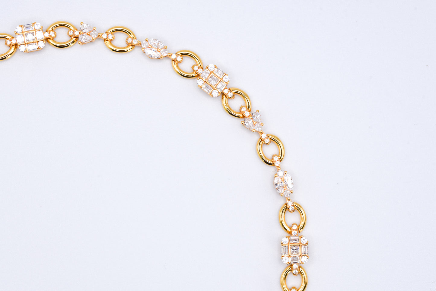 Gold color bracelet with gemstones on a light gray background