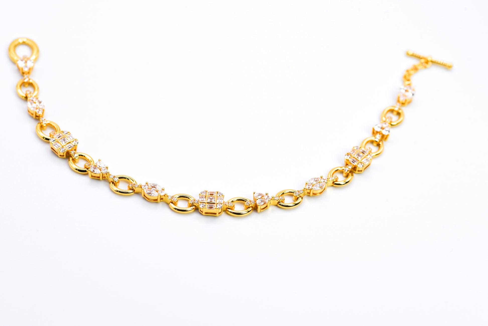 Gold color bracelet with gemstones on a light gray background