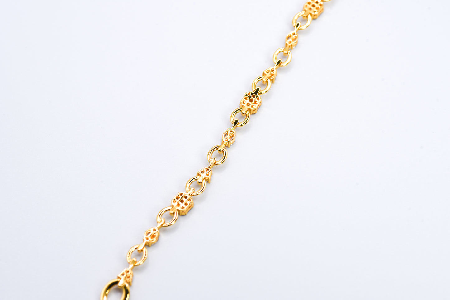Gold color bracelet with gemstones on a light gray background