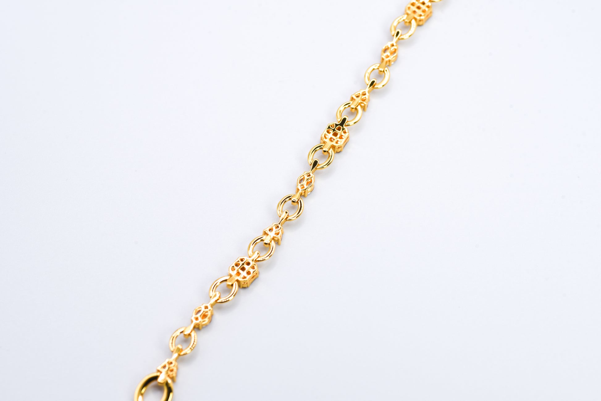 Gold color bracelet with gemstones on a light gray background