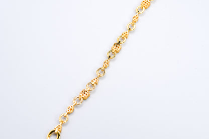 Gold color bracelet with gemstones on a light gray background