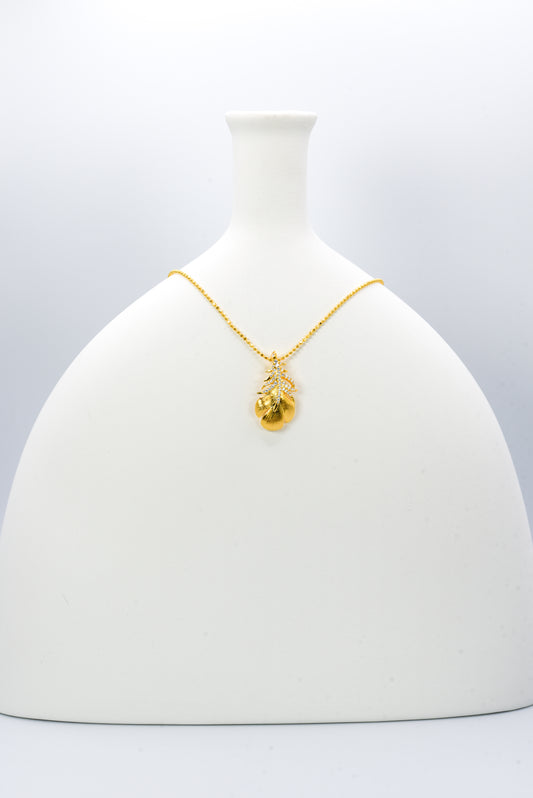 Gold color necklace with a leaf-shaped pendant on a white background