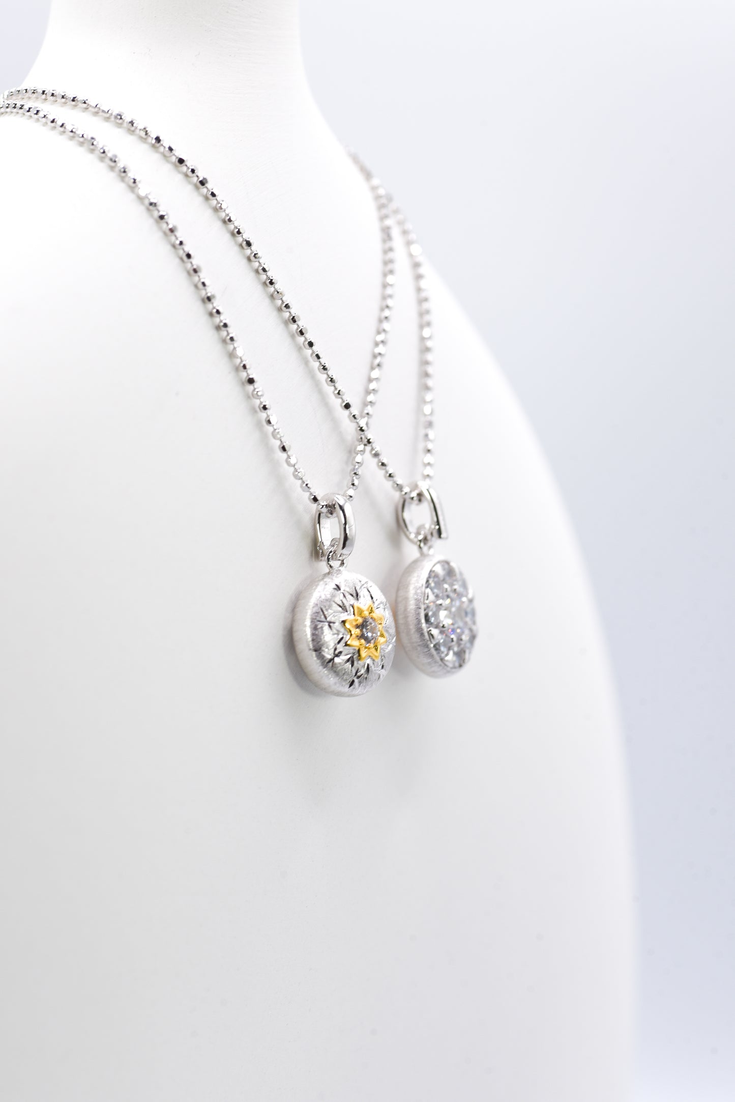 Two silver necklaces with pendants  against a white background