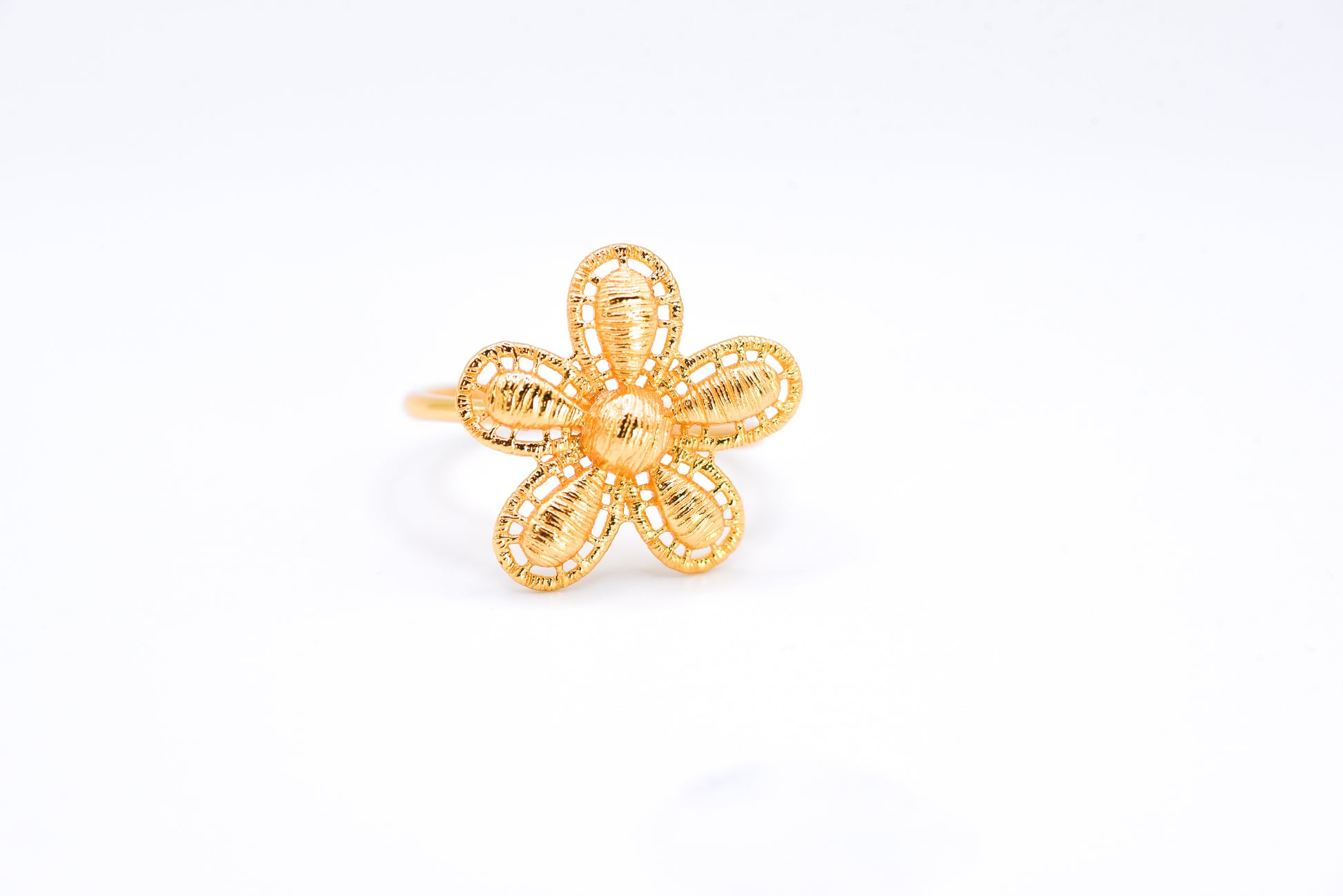 Gold flower-shaped ring on a white background