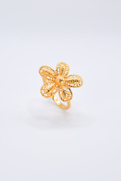 Gold flower-shaped ring on a light gray background