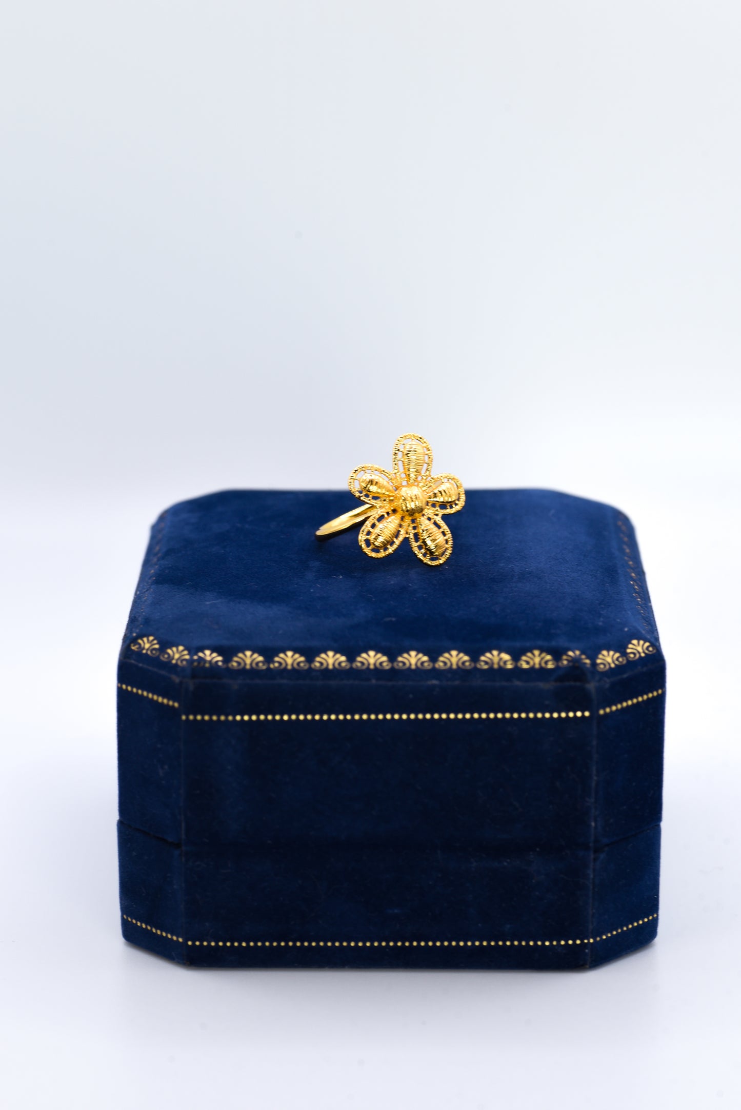 Navy blue box with gold flower ring on a white background