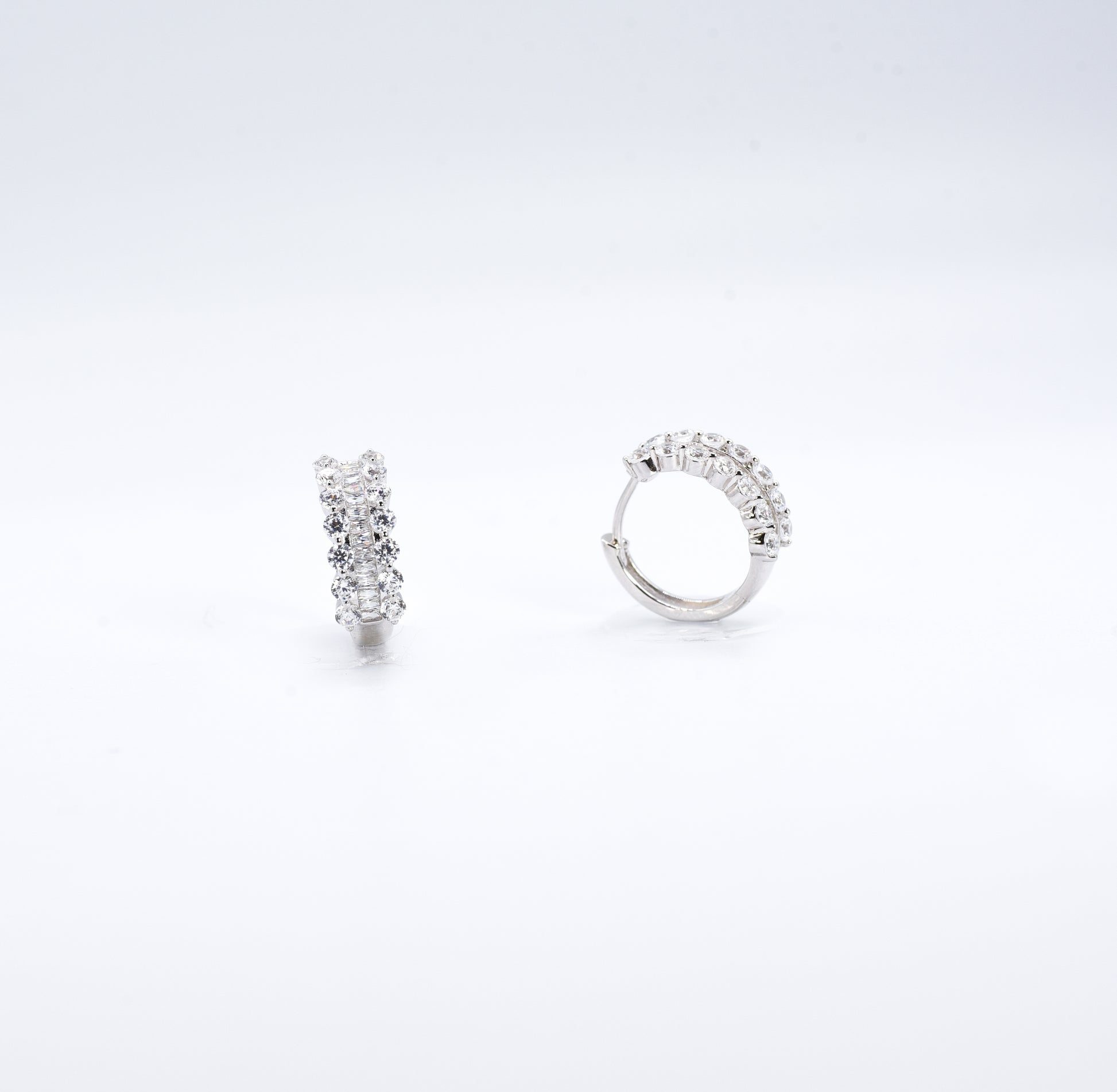 Pair of silver hoop earrings with clear gemstones on a white background