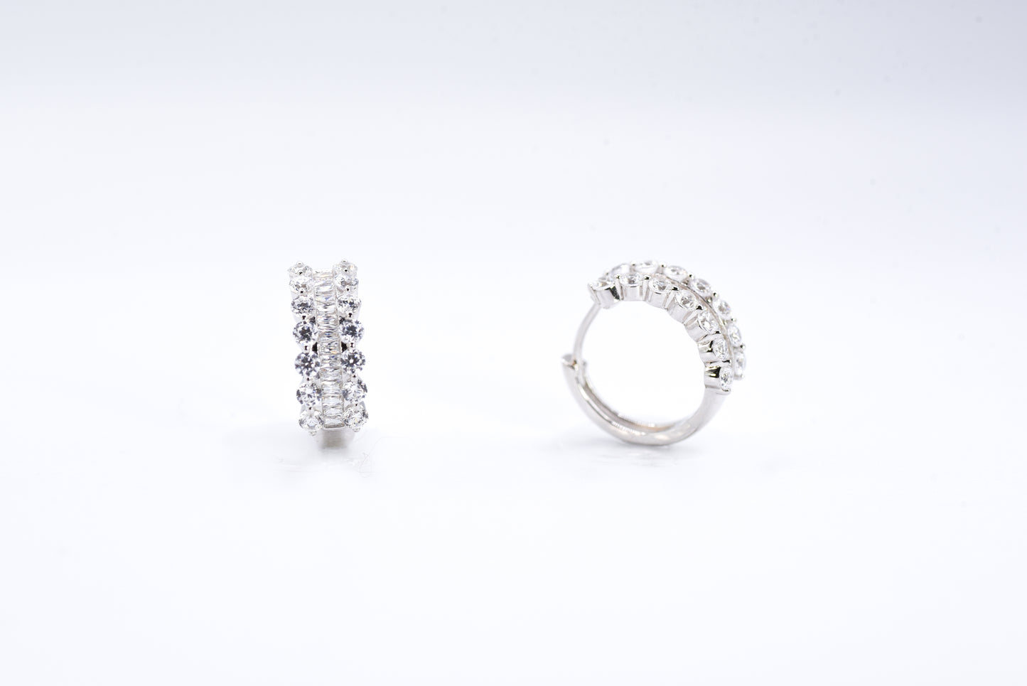 Pair of silver hoop earrings with clear gemstones on a white background