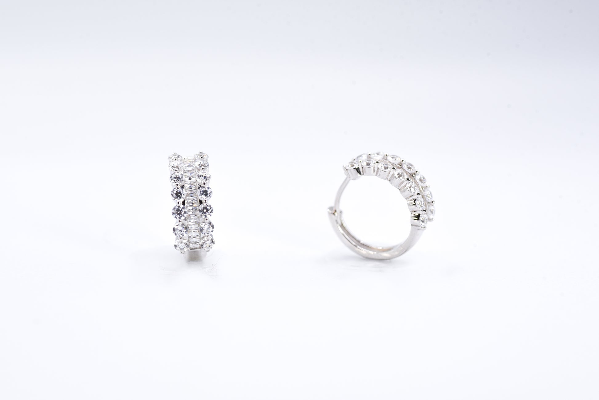 Pair of silver hoop earrings with clear gemstones on a white background