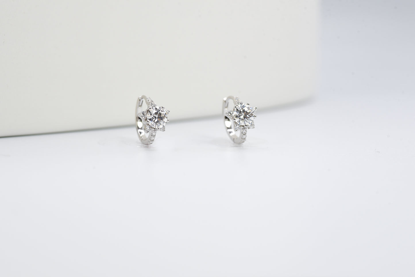 Pair of silver earrings with clear gemstones on a white background