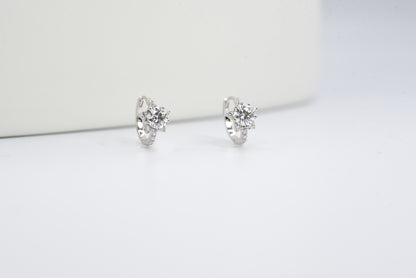 Pair of silver earrings with clear gemstones on a white background
